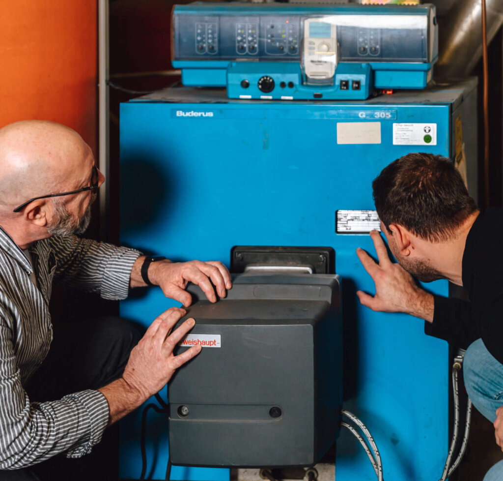 Kunde und Krastelmitarbeiter schauen sich den Zustand der Heizung an